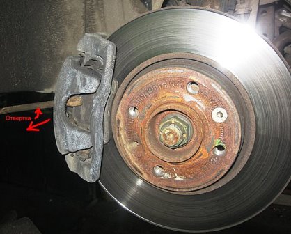 Подвешиваем передние колеса. Снимаем колесо и просовываем отвертку между тормозным диском и суппортом, отжимая тормозной цилиндр.